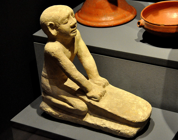 Estátua de pedra calcária de um servo egípcio moendo farinha. Do Egito moderno. Reino Antigo, 6ª Dinastia, 2250 aC. (Museu Estadual de Arte Egípcia, Munique, Alemanha).